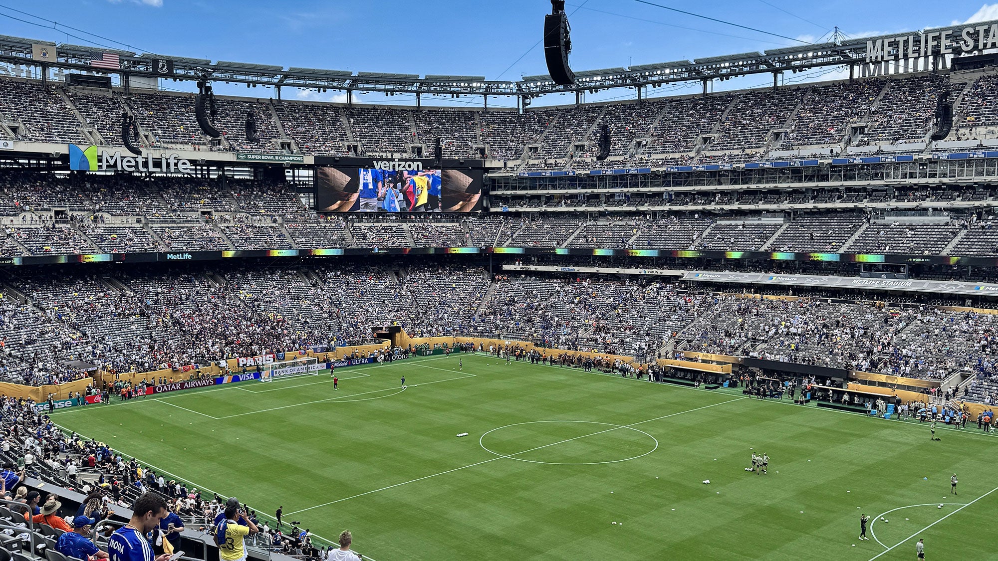 High-angle view of a soccer match at MetLife Stadium with a crowded multi-tiered seating bowl and players on the green field.