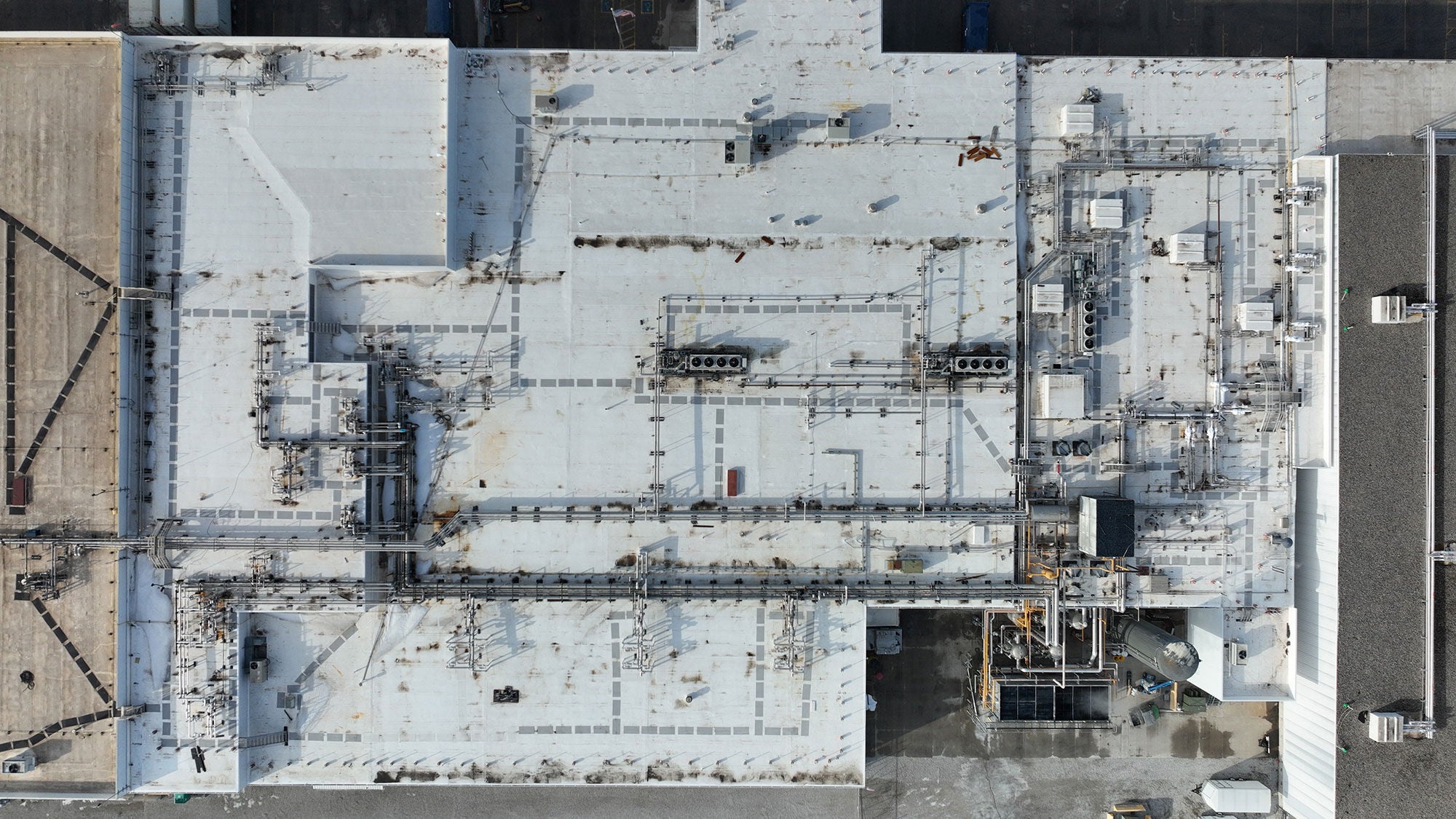 A complex roof of multiple squares that is newly surfaced, seen from directly above.