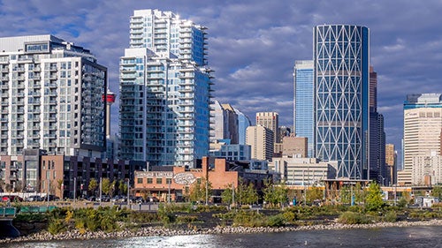 The cityscape of Calgary including several buildings set behind a river