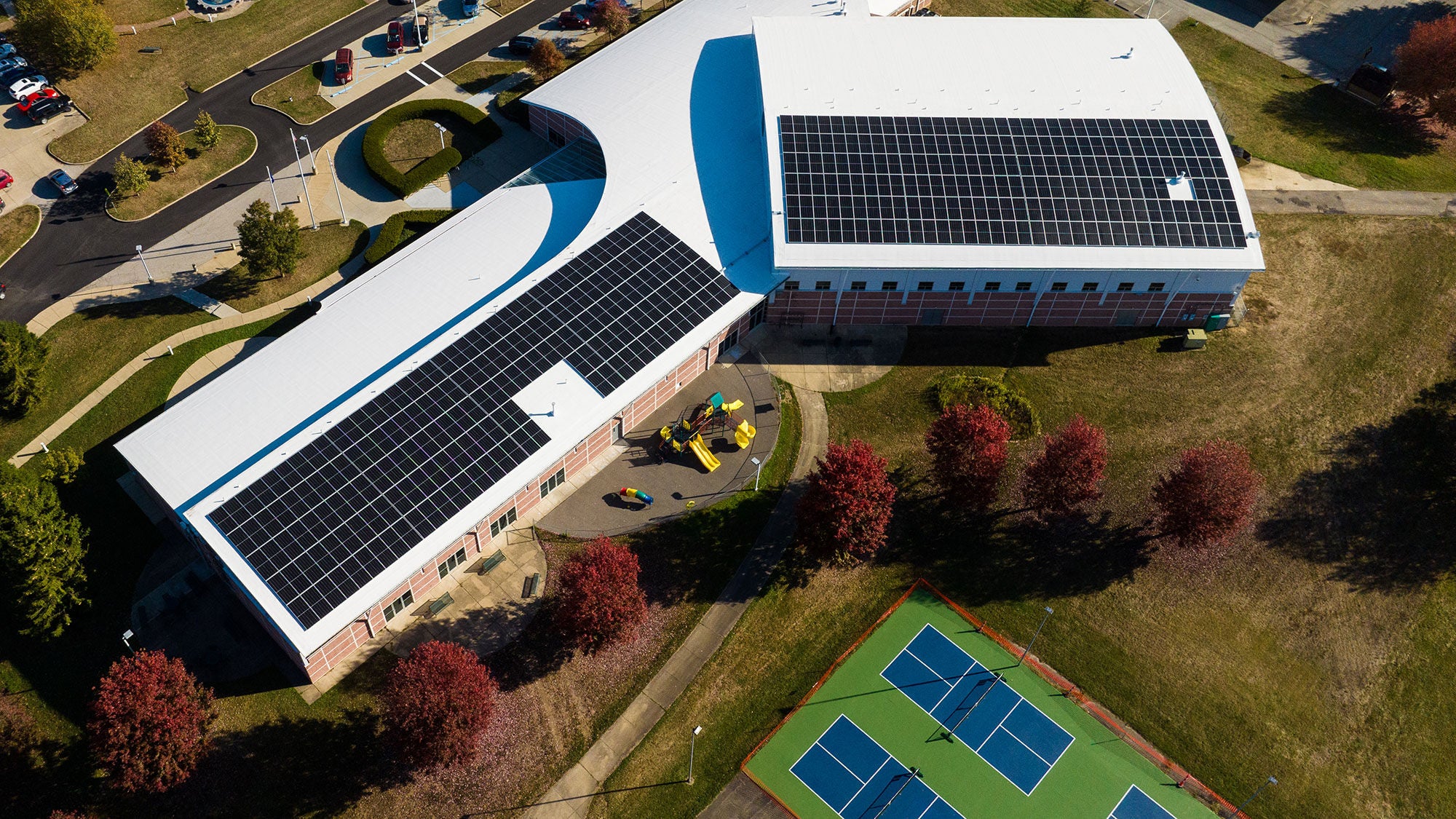 A large white roof with solar panels on a community center, seen from above