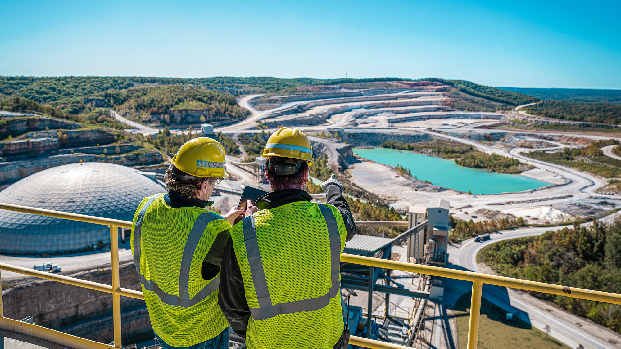 Two workers pointing out at a large quarry