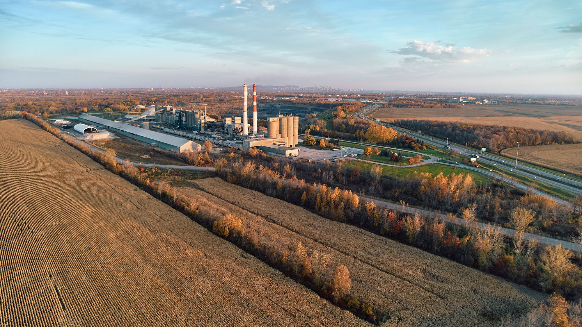 Une cimenterie située entre des champs sous un ciel bleu.