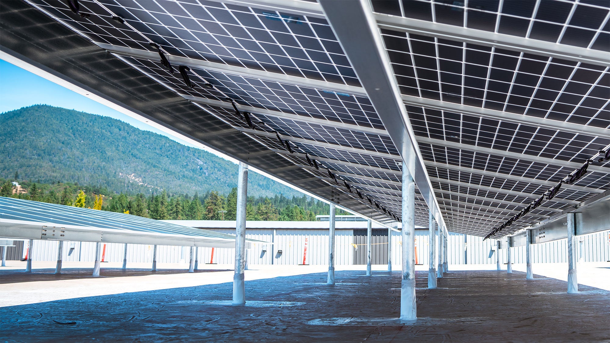 Landscape view featuring the underneath of solar panels against a mountainous background.