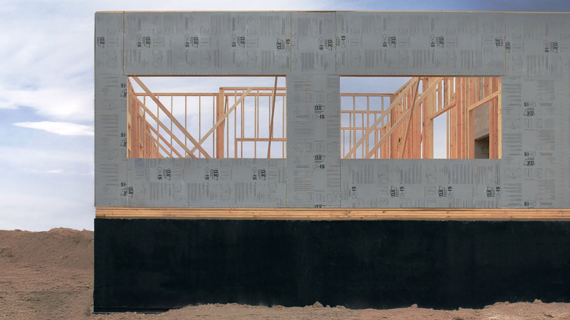 Corner of a new building under construction. White insulation panels exposed as construction takes place on the corner of the building.